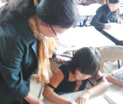 Cô giáo Oanh đang hướng dẫn em Hương viết chữ.