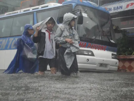 Sáng nay, học sinh trường THCS Nguyễn Tri Phương (TP Huế) phải đội mưa, lội nước đến trường.