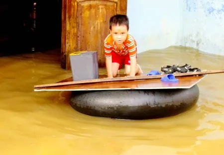 Nhà anh Lê Văn Tự (Hòa Thọ Đông, quận Cẩm Lệ, Đà Nẵng) bị ngập sâu, anh phải dùng phao đưa con ra đường chạy lụt. Ảnh: NGUYÊN KHÔI
