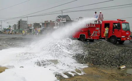 Cảnh sát PCCC phun bọt chữa cháy vào các họng cống có xăng dầu rò rỉ. Ảnh: Nguyên Khôi