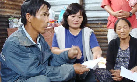 Đại diện Báo SGGP trao tiền cứu trợ cho gia đình có người bị chết do lũ ở xóm Trường. Ảnh: Quý Lâm