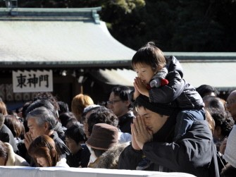 A boy sits on an adult's shoulders as they pray during a visit to Meiji shrine in Tokyo on January 1, 2010 to mark New Year's Day. (AFP photo)