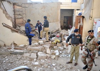Pakistan policemen stand amid the debris of a collapsed house following an explosion in Karachi on January 8, 2010. (AFP photo)