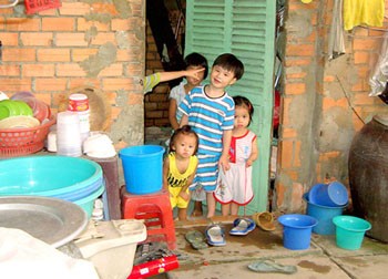 Children stand in the doorway of a makeshift 10-square-meter nursery in District 6, HCMC. Neighbors say up to 15 young children of poor laborers are housed here daily. (Photo: SGGP)