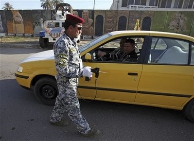An Iraqi police officer uses a scanner device to inspect a car at checkpoint in central Baghdad, Iraq, Tuesday, Jan. 12, 2010.