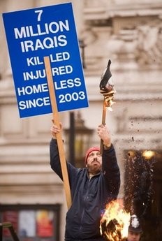 An anti-war protestor burns a mask outside the Queen Elizabeth II Conference Centre in central London.