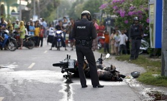 A Thai police officer checks the body of a Buddhist couple, shot and burnt by suspected Muslim militants as they were driving their motorbike in Thailand's restive southern Pattani province on January 14, 2010 (AFP photo)