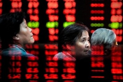 Investors are seen through stock index monitors at a trading house in Shanghai