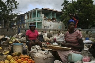 Women sell fruits and vegetables in front of a damaged house in Jacmel, Haiti, Sunday, Jan. 17, 2010. (AFP Photo)