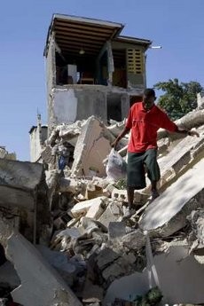 A man carries a plastic bag as he walks amidst the ruins of a house, which collapsed after last Tuesday's earthquake in Port-au-Prince January 18, 2010.