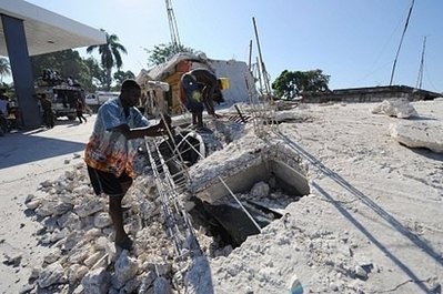 Men try to dismantle an earthquake damaged building next to a gas station in Leogane, Haiti.