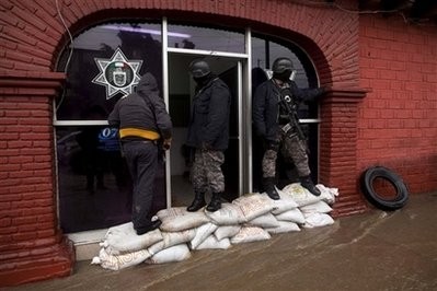 Tijuana police officers stand guard on sand bags placed to prevent the police station from flooding in Tijuana, Mexico,