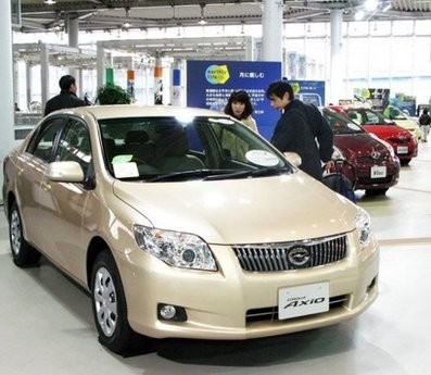 Customers are seen looking at a Toyota Corolla Axio at a Toyota showroom in Tokyo