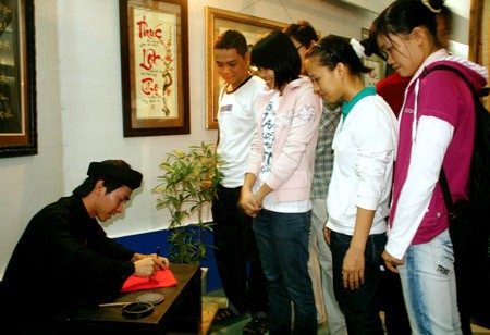 A calligrapher writes in front of a group at the exhibition of calligraphy on January 24. (Photo: SGGP)