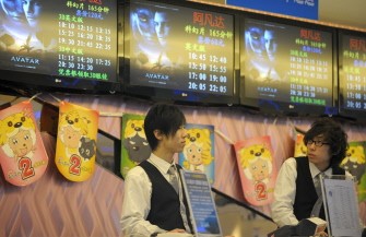 Employees wait for customersbeneath monitors displaying the time table of the movie Avatar at a cinema in Beijing on January 21, 2010. AFP photo