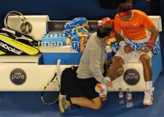 Spanish tennis player Rafael Nadal (R) is treated by an official during his men's singles quarter-final match against British opponent Andy Murray on day nine at the Australian Open tennis tournament in Melbourne on January 26, 2010. AFP photo