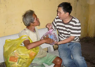 Phân chia thịt cho người sống lang thang trên các vỉa hè. Ông Trần Ích Phú, 61 tuổi, cảm thấy ấm lòng khi nhận phần quà thịt kho trứng và bánh tét.