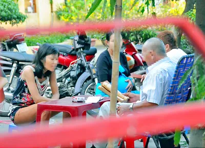 Một “thầy” đang bói cho hai phụ nữ trước Lăng Lê Văn Duyệt, Bình Thạnh. Ảnh: AN DUNG