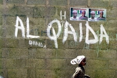 In this April 18, 2003, file photo a girl walks past a wall with graffiti about the al-Qaida network in a Muslim area of the northern city of Kano, Nigeria.
