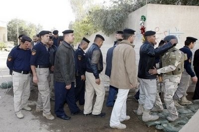 Iraqi policemen and soldiers are searched by security forces outside a polling station in Baghdad. (AFP Photo)