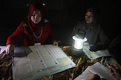 Iraqi election officials count votes using the light of a lamp due to an electricity outage at a polling station in Baghdad's Shiite bastion of Sadr City.