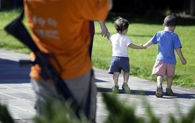 File photo shows two Israeli boys and their mother walking in the Southern Gaza Strip settlement of Ganei Tal close to an armed Israeli settler.
