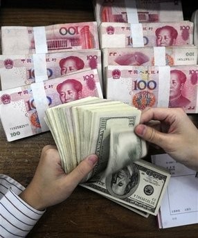 In this Oct. 16, 2009 file photo, a bank clerk counts U.S. 100 dollar bills near bundles of Chinese renminbi notes at a bank in Hefei, in central China's Anhui province.