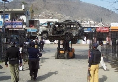 Policemen make way for fork lift truck carrying the wreckage of a vehicle from the site after a suicide attack in Saidu Sharif, on the outskirts of Mingora, Swat valley, on March 13. AFP photo