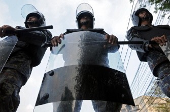 Riot policemen stand guard outside Government House as unseen supporters of deposed Thai premier Thaksin Shinawatra gather for a mass rally in downtown Bangkok on March 14, 2010. AFP photo