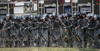 Thai soldiers secure an entrance gate as red-shirted supporters of deposed Thai premier Thaksin Shinawatra (not seen) wave flags and shout slogans during an anti-government protest outside a military baracks in Bangkok on March 15, 2010. AFP Photo