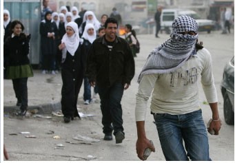 Palestine school girls stands behind a masked protester in Jerusalem on March 16,2010. (AFP Photo)
