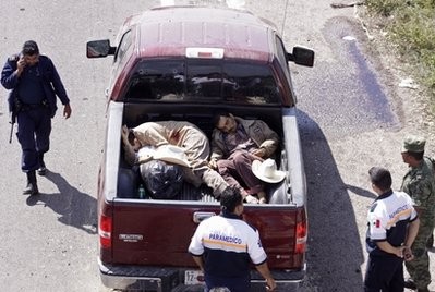 Police, Army and paramedics stand next to a pick-up truck with the bodies of two men dead in the cabin on the Mazatlan-Culiacan highway near the town of Elota, Mexico, Saturday March 20, 2010.