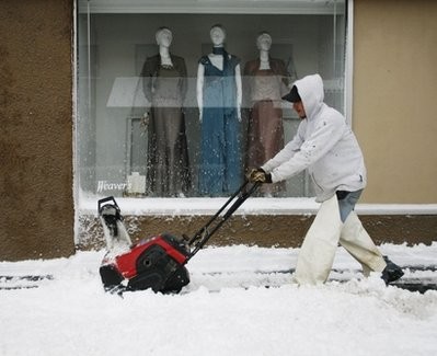 Toby Sumner, of Ritzman Lawn Service, clears snow in front of a Weaver's Department Store window Saturday, March 20, 2010, in Lawrence, Kan