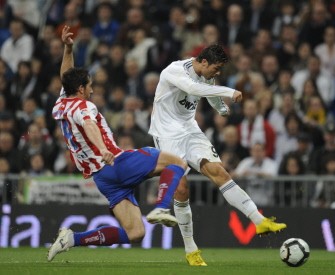 Real Madrid's Portuguese forward Cristiano Ronaldo (L) kicks a ball against Sporting Gijon's midfielder Diego Camacho during their Spanish League football match at Santiago Bernabeu stadium in Madrid on March 20, 2010. AFP PHOTO