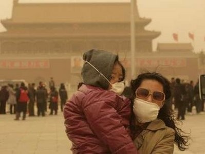 Tourists wearing face masks stand amid a sandstorm on Tiananmen Square in Beijing March 20, 2010.