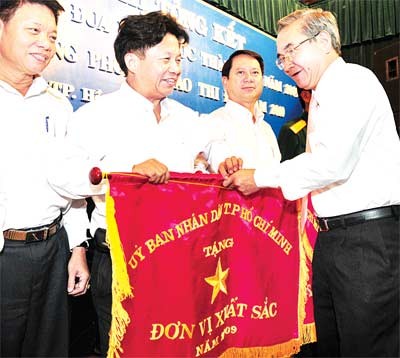 Tran The Tuyen (2nd L), editor-in-chief of Sai Gon Giai Phong, accepts an emulation flag for “Outstanding Labor Unit in 2009,” on behalf of Sai Gon Giai Phong newspaper, from Nguyen Trung Tin (R), vice chairman of the Ho Chi Minh City People’s Committee (Photo: SGGP)