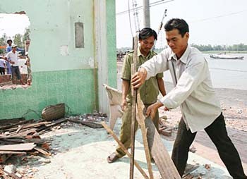 Residents living along Highway 91 in Binh My Commune, Chau Phu District, An Giang Province evacuate their homes after a section of the roadway suddenly fell into the Hau River March 22-23 (Photo: SGGP)