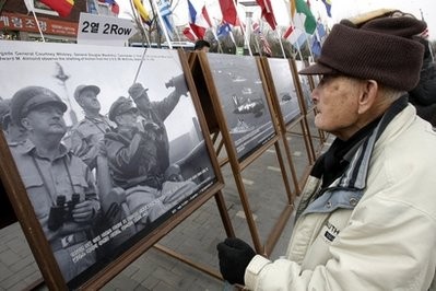 A South Korean elderly man watches a documentary picture showing U.S. Gen. Douglas MacArthur, commander in chief of U.N. forces in the Korean War, second from right, at a photo exhibition of Korean War (1950-1953) in Seoul, South Korea.