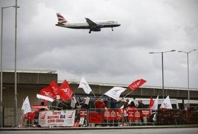 A British Airways plane flies over striking British Airways cabin crew at Heathrow Airport. AFP photo