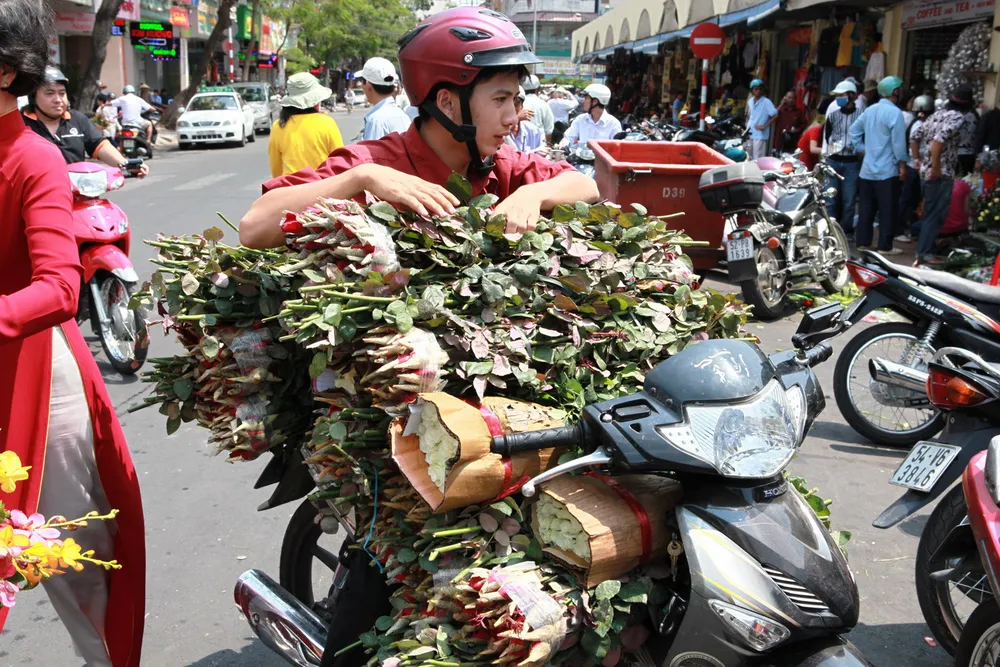 Một thanh niên đang chở hoa đến bỏ mối cho một cửa hàng hoa tươi tại chợ Bến Thành.
