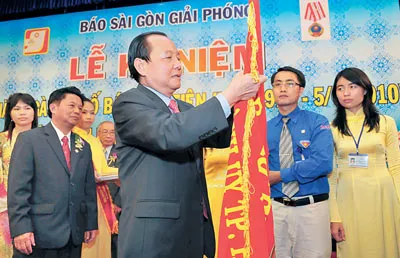 Bí thư Thành ủy TPHCM Lê Thanh Hải gắn Huân chương Độc lập hạng ba lên cờ truyền thống của báo SGGP. Ảnh: VIỆT DŨNG