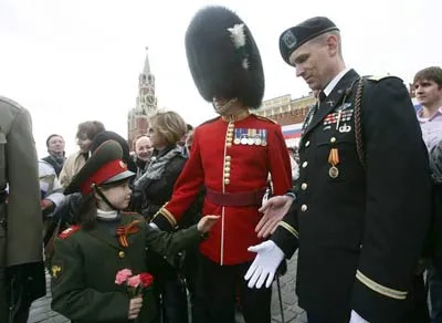 Các sĩ quan quân đội Anh và Mỹ chào hỏi một bé gái Nga trong bộ quân phục trên quảng trường Đỏ.