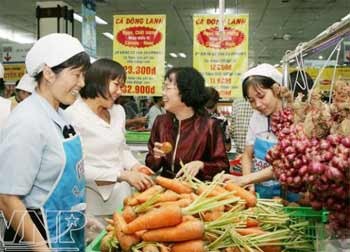 Merchants and customers share smiles at a supermarket in HCMC, where the authorities have launched a market stabilization plan for the sake of consumers (Photo: vietnam.vnanet.vn)