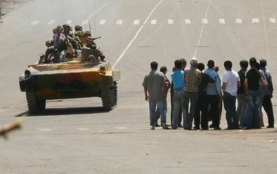 Kyrgyz soldiers on an armoured vehicle drive past a group of people in Osh.