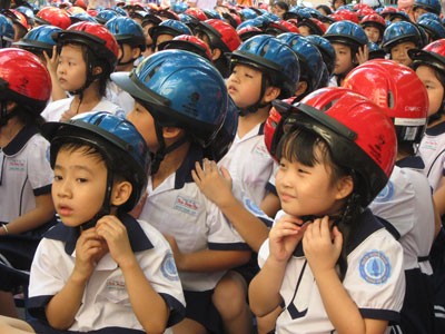 The Asia Injury Prevention Foundation gives helmets to pupils of the Tran Hung Dao Primary School in HCMC. The foundation often provide training and helmet to Vietnamese young people to prevent injuries in heads (Photo: Nguoi Lao Dong)
