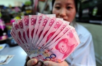 A shop worker holds a display of 100 yuan notes in Beijing on June 20, 2010