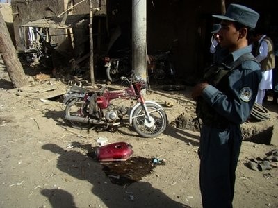 An Afghan policeman stands at the scene of a blast in Lashkar Gah, the capital of Helmand province, south of Kabul, Afghanistan, Sunday, June 20, 2010.