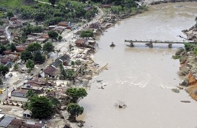 In this photo released by Agencia Brasil, a broken bridge stands in a swollen river after heavy rains in the city of Barreiros in Pernambuco state, Brazil, Wednesday, June 23, 2010.