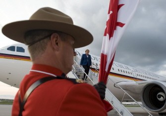 A mountie holding a Canadian flag stands guard as German Chancellor Angela Merkel steps off her plane after arriving at the airport of Toronto on June 24, 2010. AFP