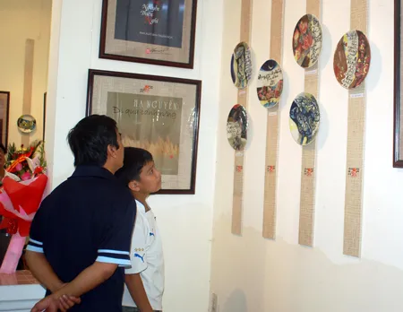 Du khách thích thú với triển lãm Gốm đề thơ của họa sĩ Trần Đỗ Nghĩa. Ảnh: Nguyễn Hùng